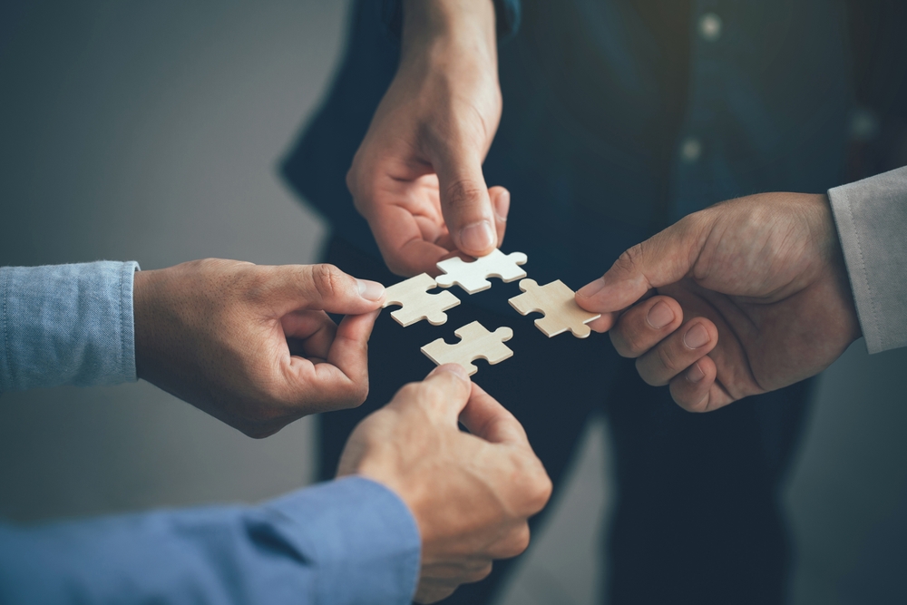 Concept of teamwork and partnership. Hands join puzzle pieces in the office. 