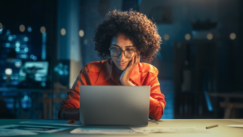 Portrait of a Happy Successful Businesswoman Using Laptop Computer in Creative Agency in the Evening.