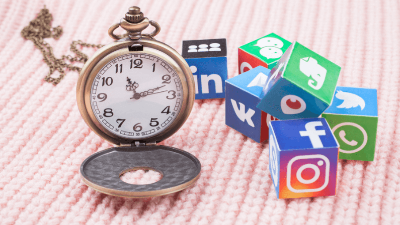 paper cubes with popular social network logos and clocks with chain in a shape of heart on a knitted texture Facebook, Insta etc