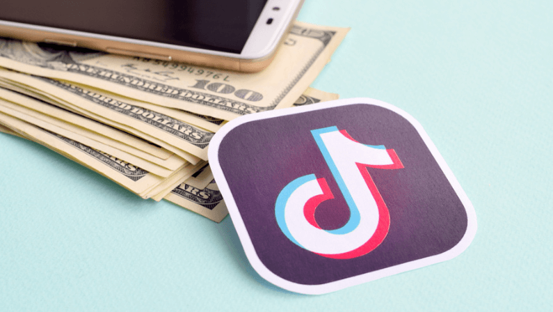 Tiktok paper logo lies with envelope full of dollar bills and smartphone