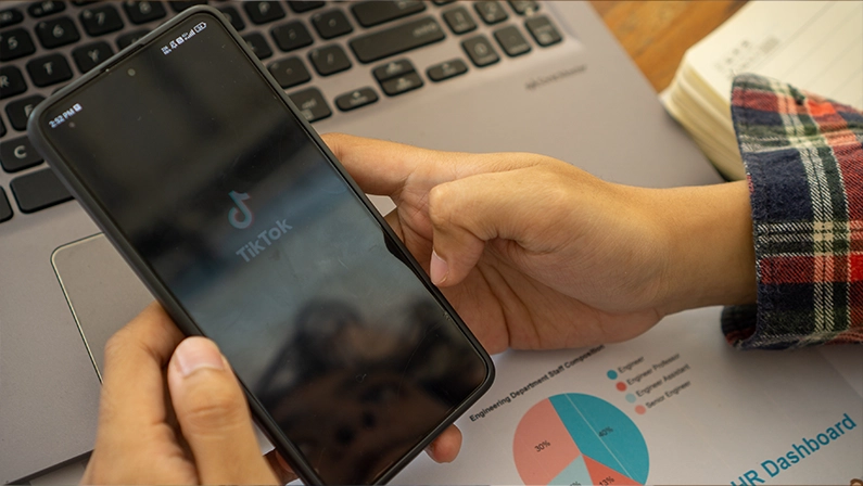 Bogor, Indonesia - July 13, 2024: Close up a man hand hold smartphone with loading screen opening Tiktok app logo. A man hand is holding a cellphone opening the TikTok application