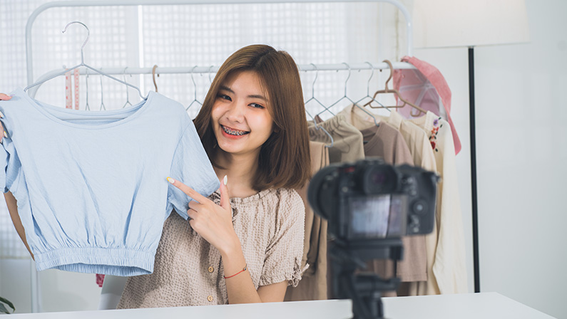 Happy young, lovely attractive Asian female blogger or vlogger looking at the camera and talking on recording video at home office. Social media influencer people or content maker concept.
