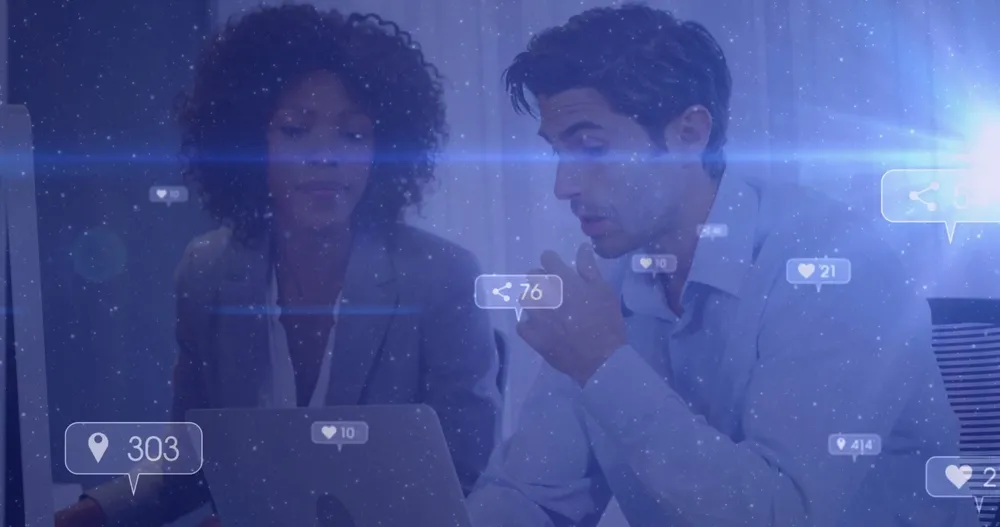 Collaborating colleagues reviewing social media metrics at office, with laptop and floating icons.