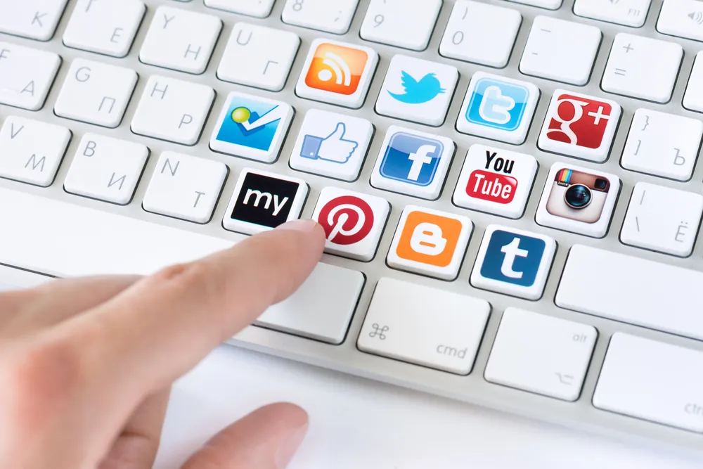 Male hand pointing on keyboard with logotypes collection of well-known social network brand's