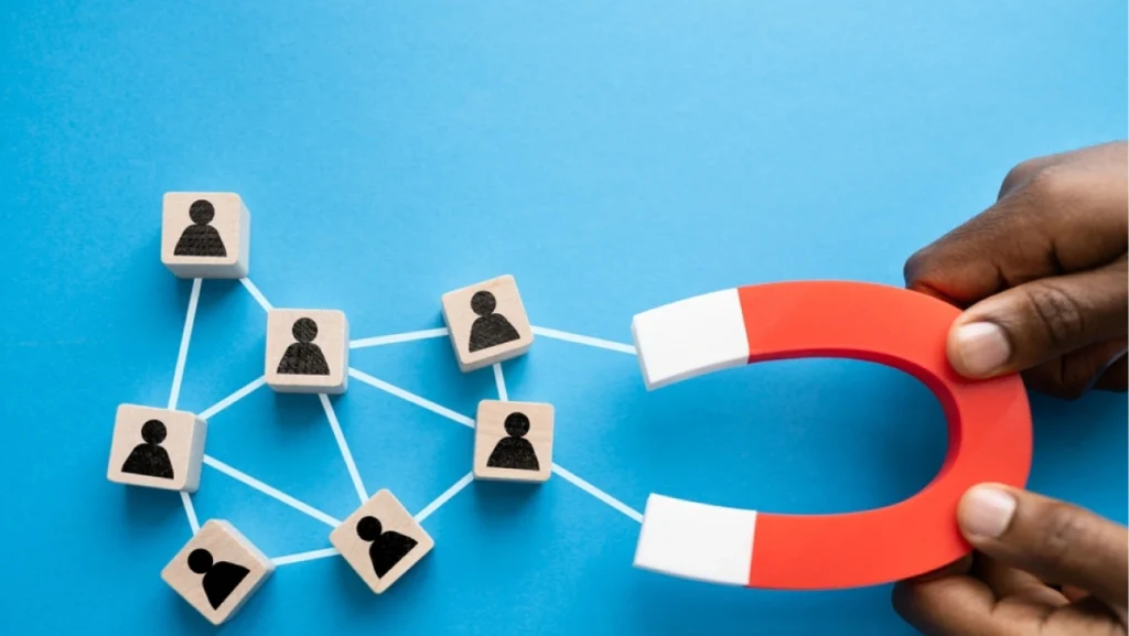 Hand holding magnet attracting icons of people, symbolizing a high-converting lead magnet generating leads.
