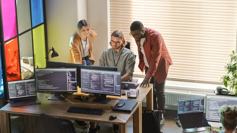 Male CEO and Female CTO Talking to Software Engineer Team Lead In Creative Office Space.