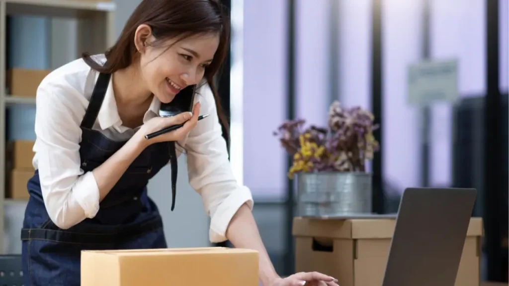 Female small business owner checks products for customers via phone.