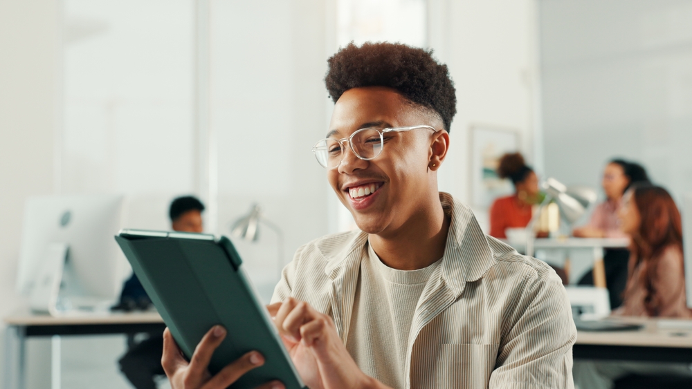 A man smiling while holding his tablet