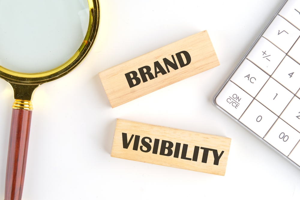 Words Brand visibility on wooden blocks beside a magnifying glass