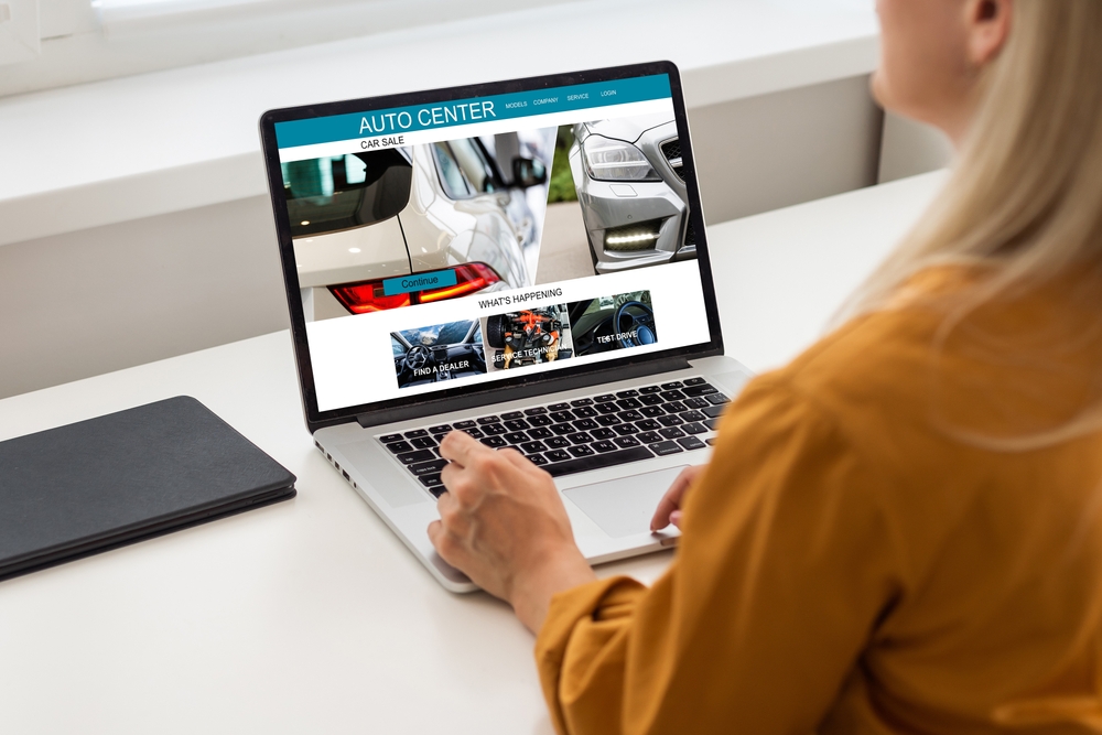 Woman in front of her laptop featuring a Auto Center website for car sale