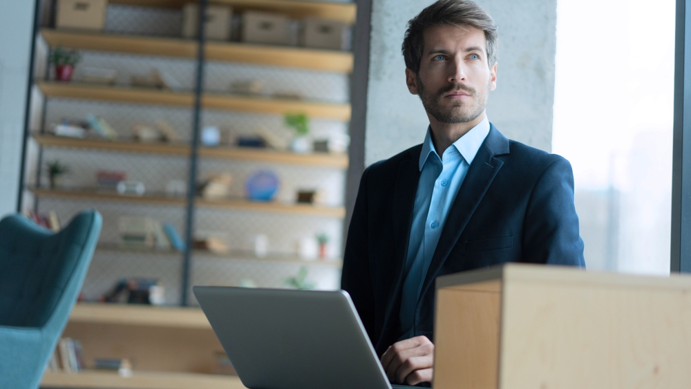 Businessman looking away with his laptop in the office