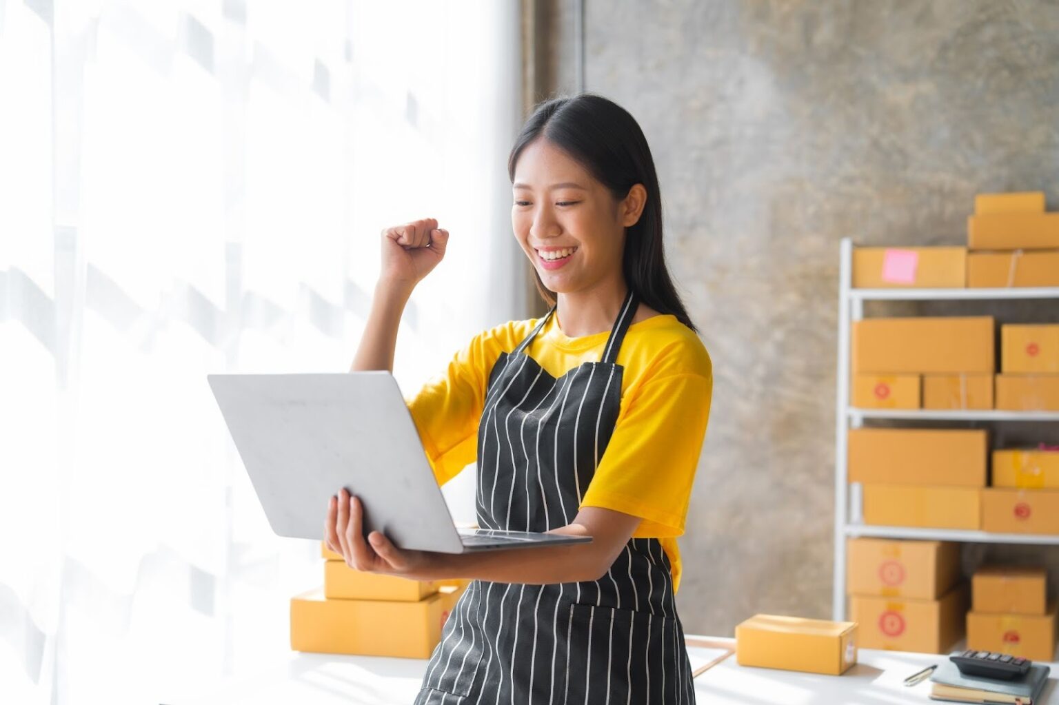 owner of a start up business happy holding a laptop