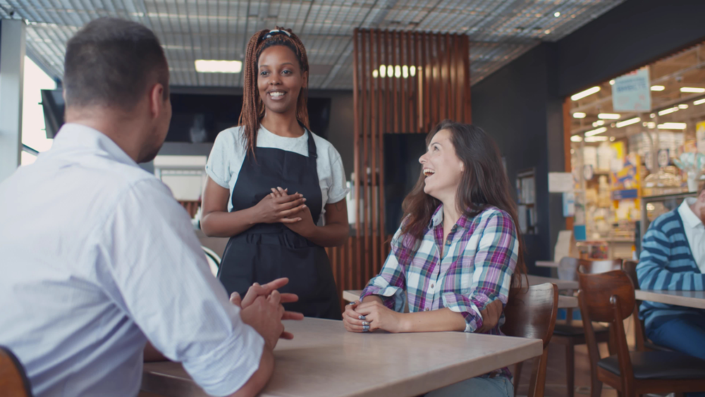 Young couple placing order in restaurant or bistro with waiter