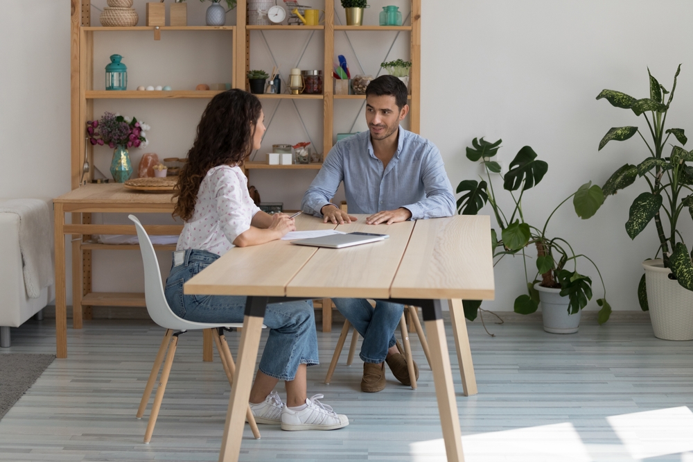 In cozy workplace two young millennial, negotiating seated at desk.