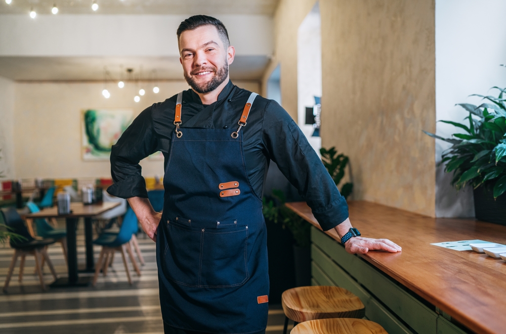 Portrait of happy smiling small business owner dressed in a black wearing apron