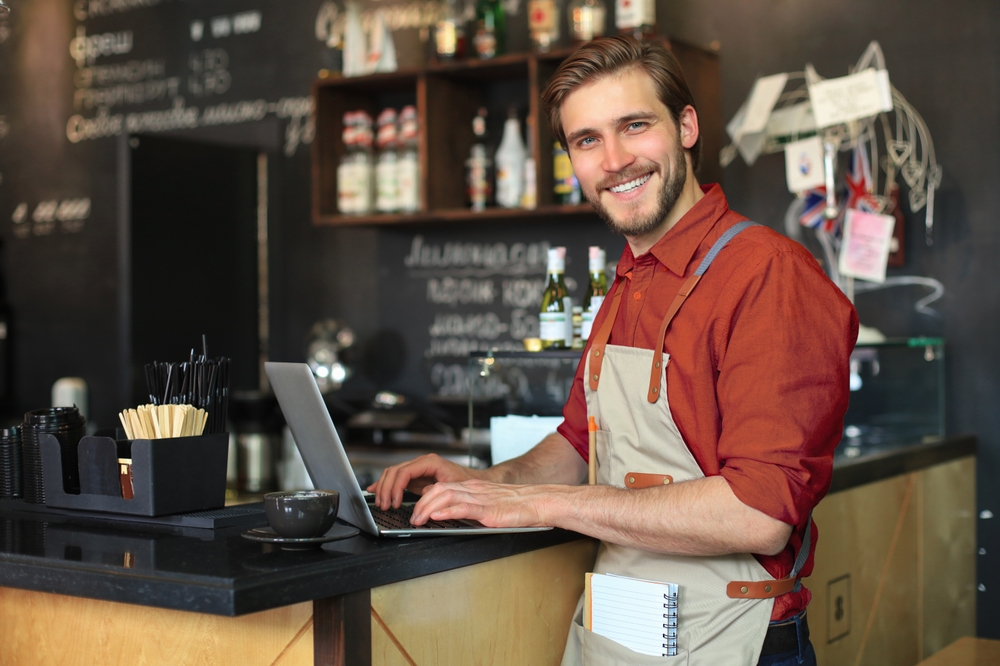 Restaurant manager working on laptop at the bar counter