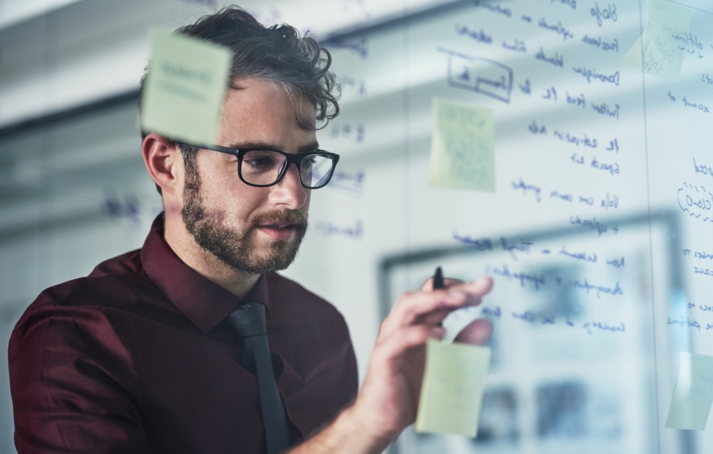 Glass wall, review or man in agency with planning, insight or creative strategy in brainstorming