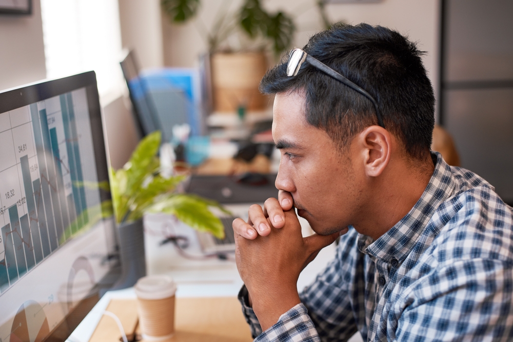 A businessman scrutinises a bar graph at his desk in the office