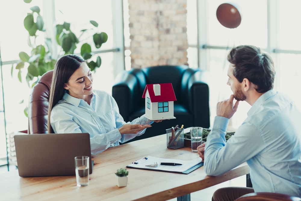 Professional business interaction showcasing a house model