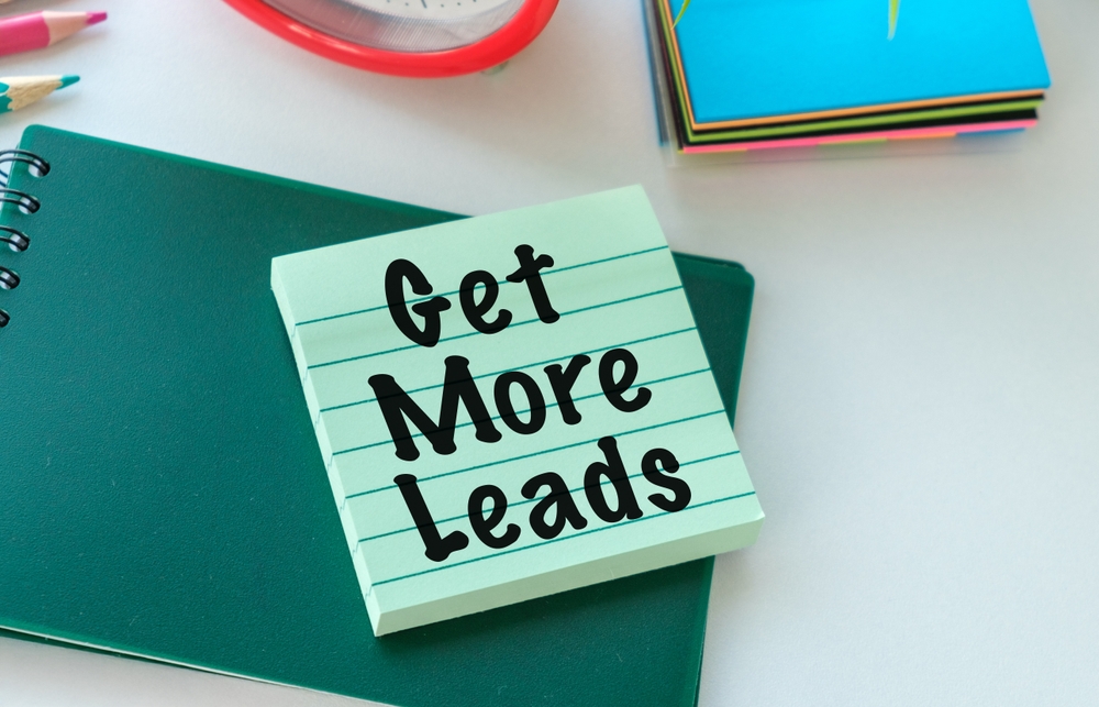 A green notebook with a sticky note on it that says Get More Leads