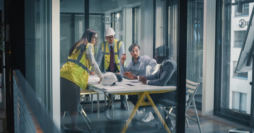 Business Professionals Meet in a Glass Office to Review Construction Plans