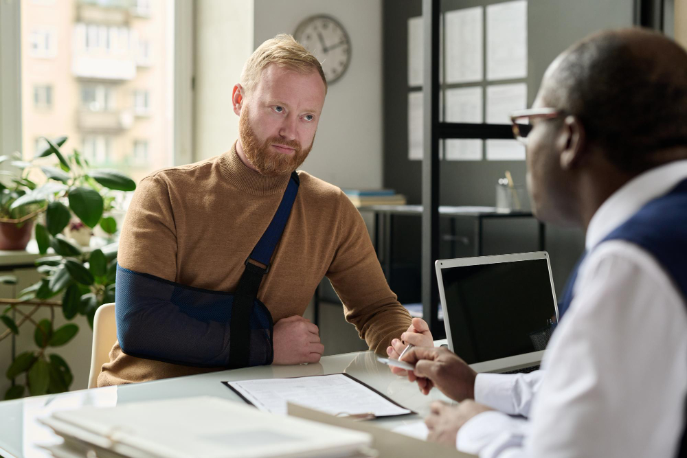 Portrait of man with hand in sling talking to insurance broker after workplace