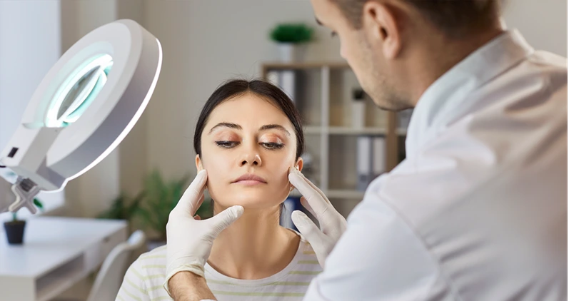 Woman preparing for plastic surgery, being examined by plastic surgeon in clinic under lamp. Female model visiting beautician for facial treatment and skin care. Beauty procedures and rejuvenation