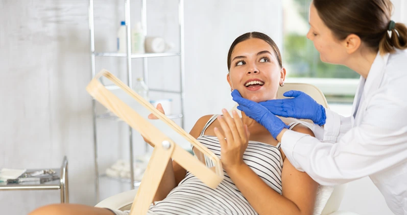Woman cosmetologist examines patients face after lifting procedure and gently palpates touches chin area with finger