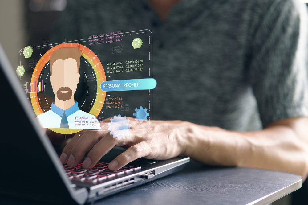 A person interacting with a laptop displaying a digital personal profile. 