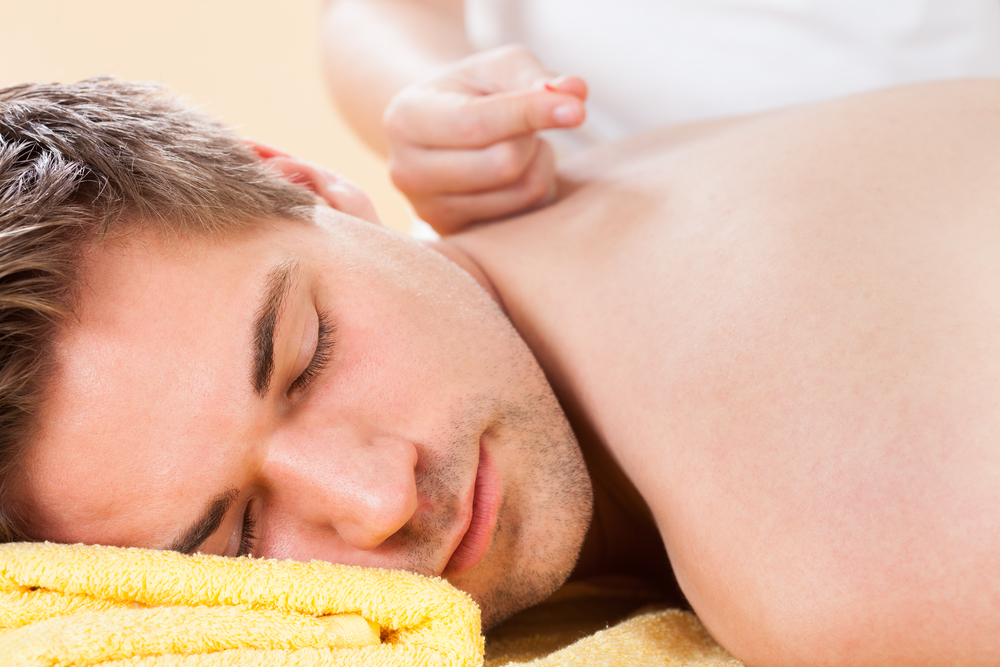 Closeup of relaxed young man receiving acupuncture treatment in spa