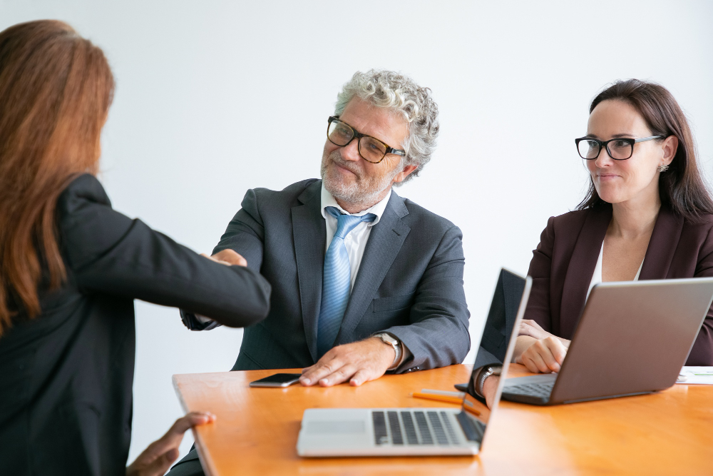 Red-haired businesswoman greeting bearded colleague