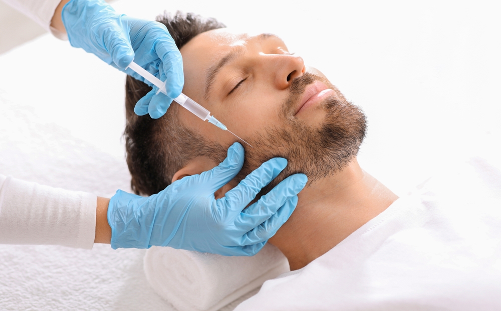 Bearded man getting beauty injection in face in luxury salon
