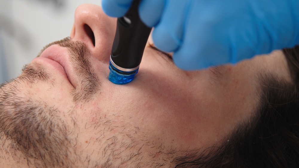 A man undergoes hydrofacial vacuum facial cleansing, rejuvenation, moisturizing facial procedure in a beauty clinic. 