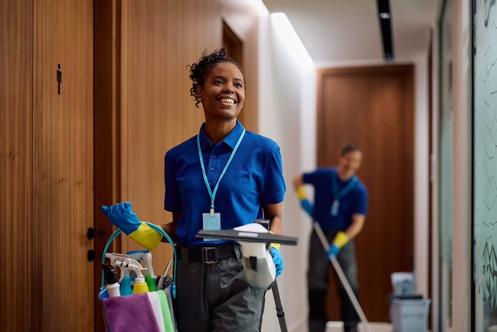 Happy African American facilities maintenance professional with cleaning supplies