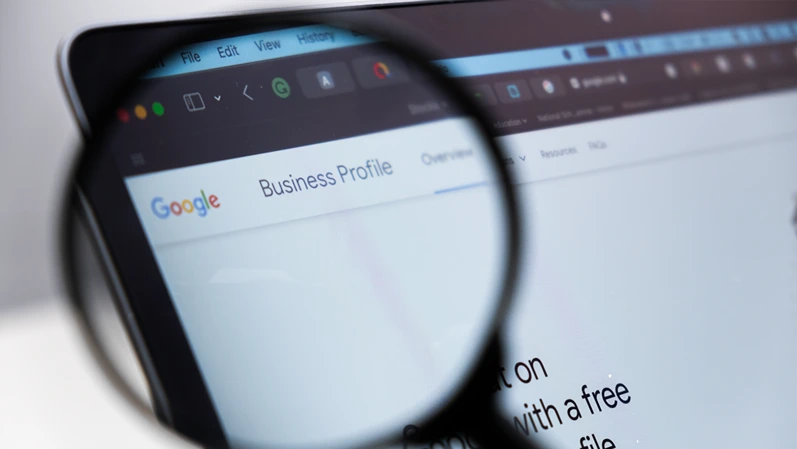Google Business Profile logo on the screen of laptop through magnifying glass, December 2023, Prague, Czech Republic