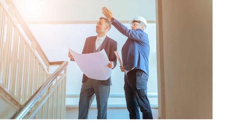 Architect and engineer reviewing blueprints at construction site