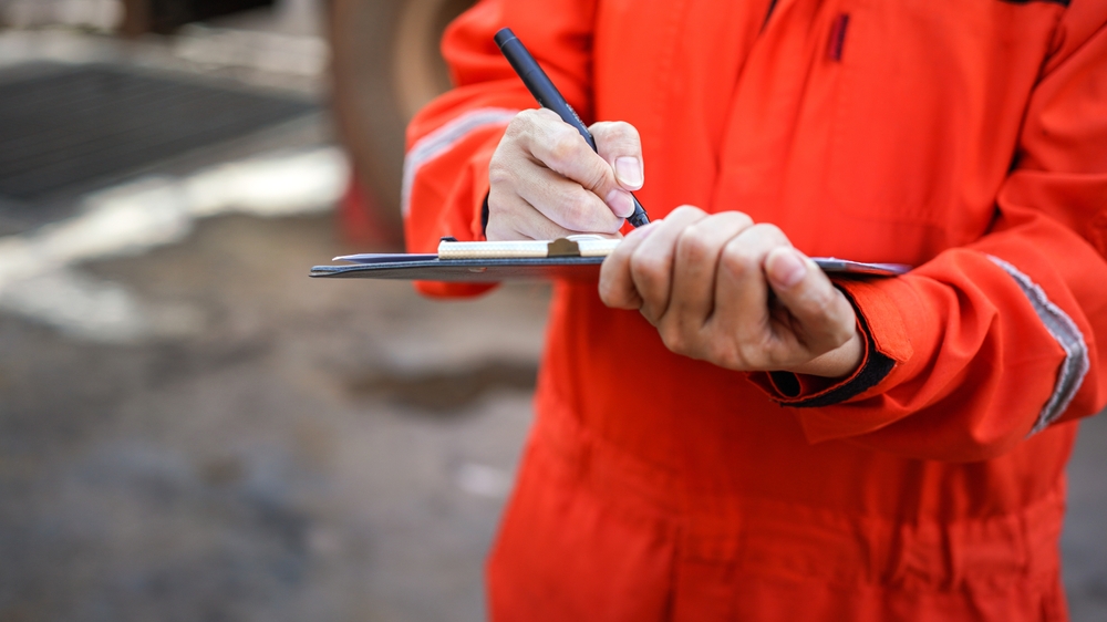 A safety officer is writing on the checklist