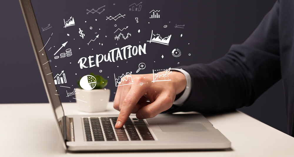 Businessman working on laptop with REPUTATION inscription, modern business concept