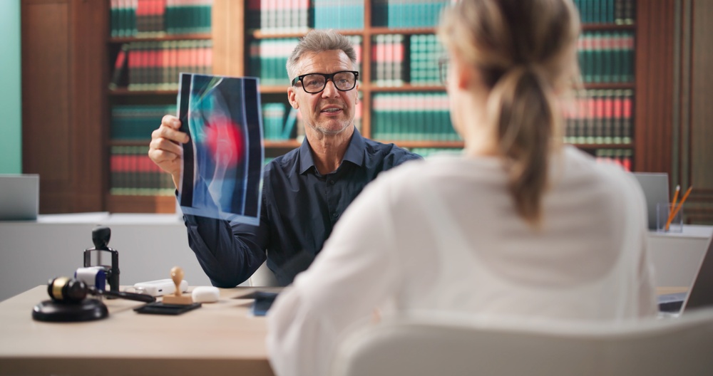 Lawyer And Female Client Review Medical Records Discussing Surgical Error Claim.