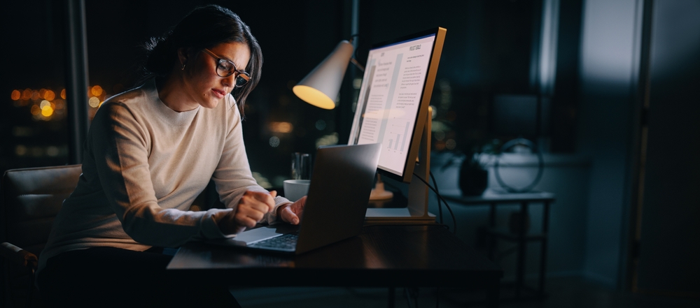 Caucasian woman works late from her home office, typing her ideas on her laptop.