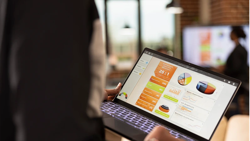 Selective focus on device screen displaying business analytics charts. Rearview closeup of african american person walking in office, reviewing financial graphs and evaluating kpi on laptop.