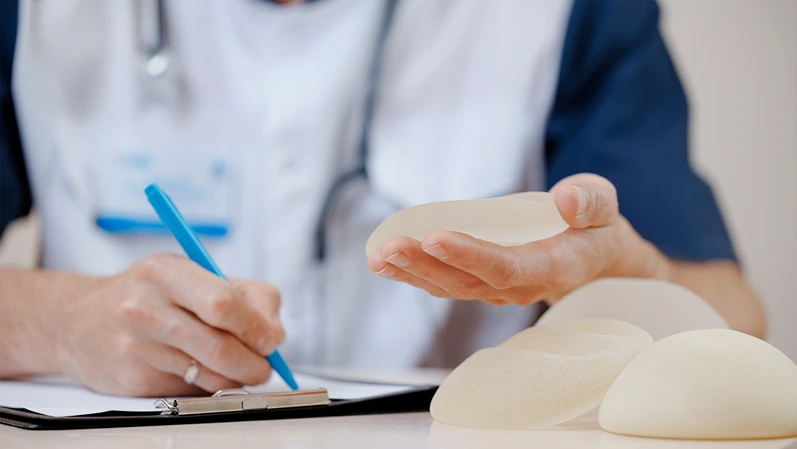 Doctor discussing silicone breast implants at plastic surgery clinic.