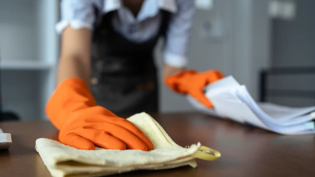 Woman maid cleaning and wiping the table with microfiber cloth in office