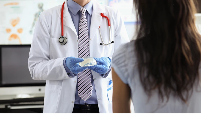 Pastic surgeon demonstrates a silicone implant to patient. Breast augmentation surgery concept