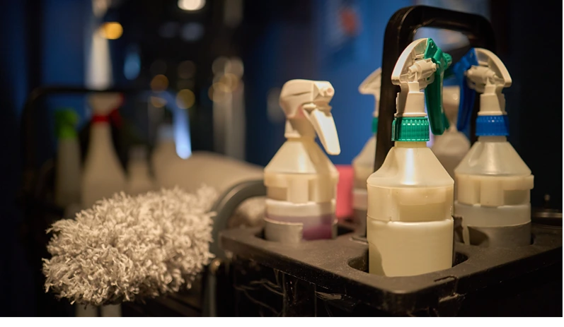 Close up of cleaning supplies standing in caddy, showing spray bottles and duster for sanitation workflow. Supporting janitorial service, hygiene marketing, facility maintenance promotion