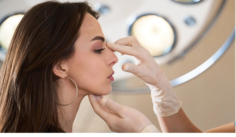 Surgeon plans nasal septum correction for beautiful facial harmony. Plastic surgeon examines female nasal septum to plan aesthetic beauty enhancement. Rhinoplasty Aesthetic Transformation.