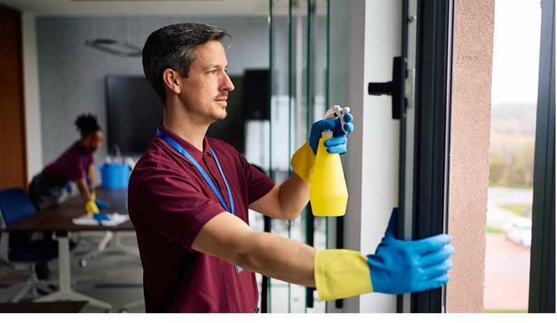Commercial cleaner using spray bottle to clean office windows. Copy space.
