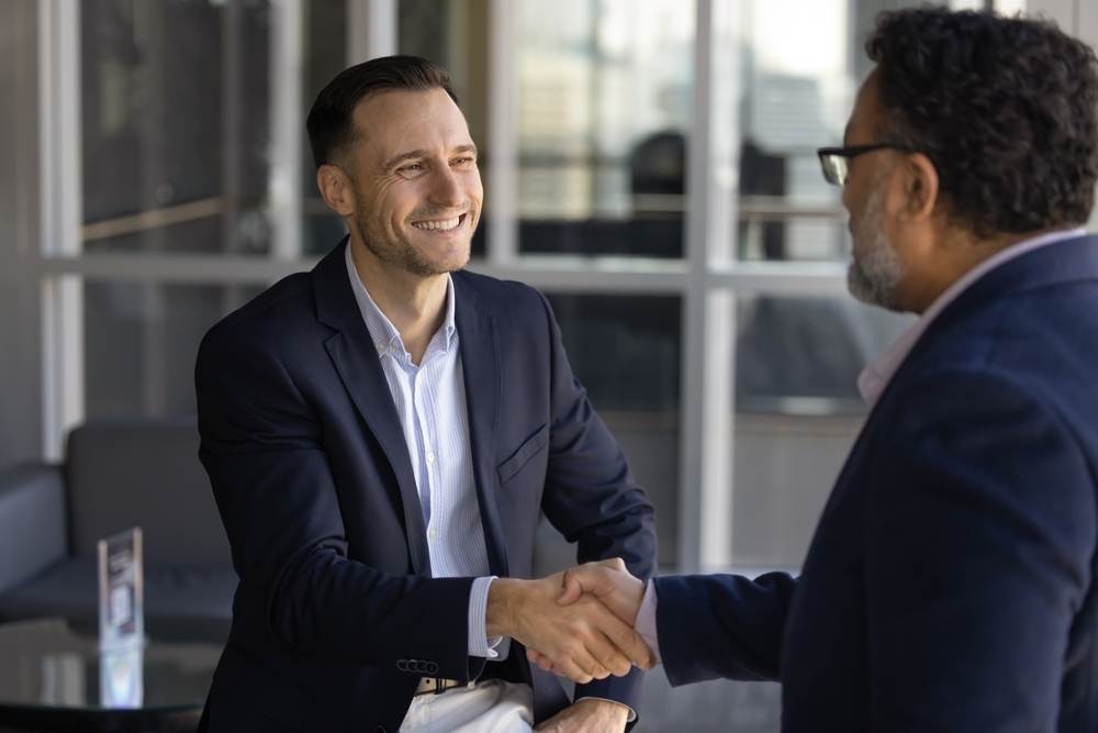 Happy successful financial consultant man shaking hands with older Indian male client