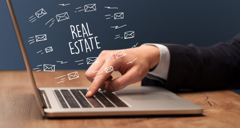 Businessman working on laptop with REAL ESTATE inscription, online shopping concept