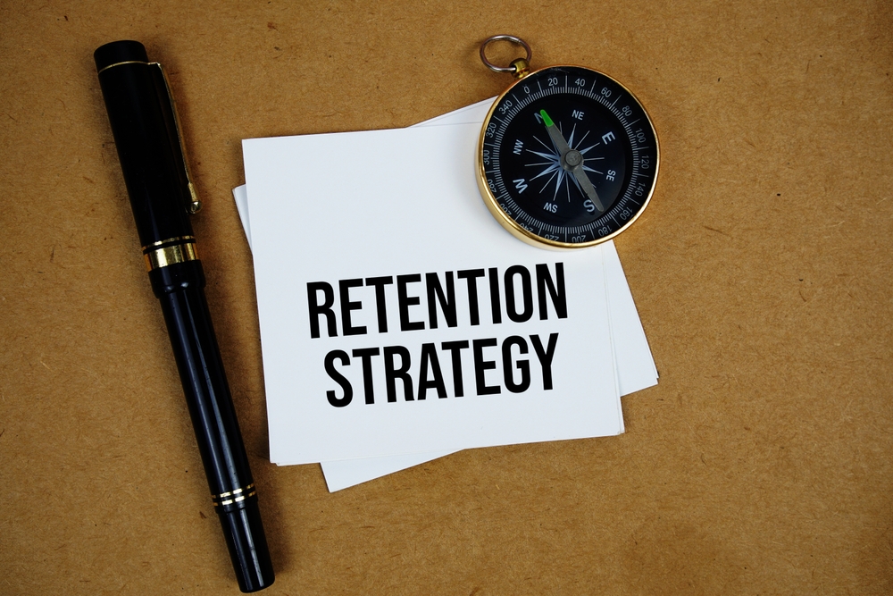Retention Strategy text on sticky note with compass on paper craft background